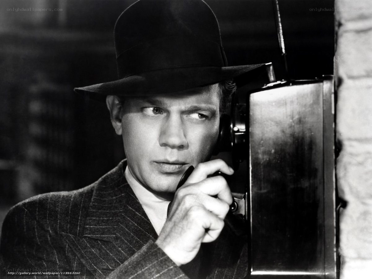 Man in hat using payphone