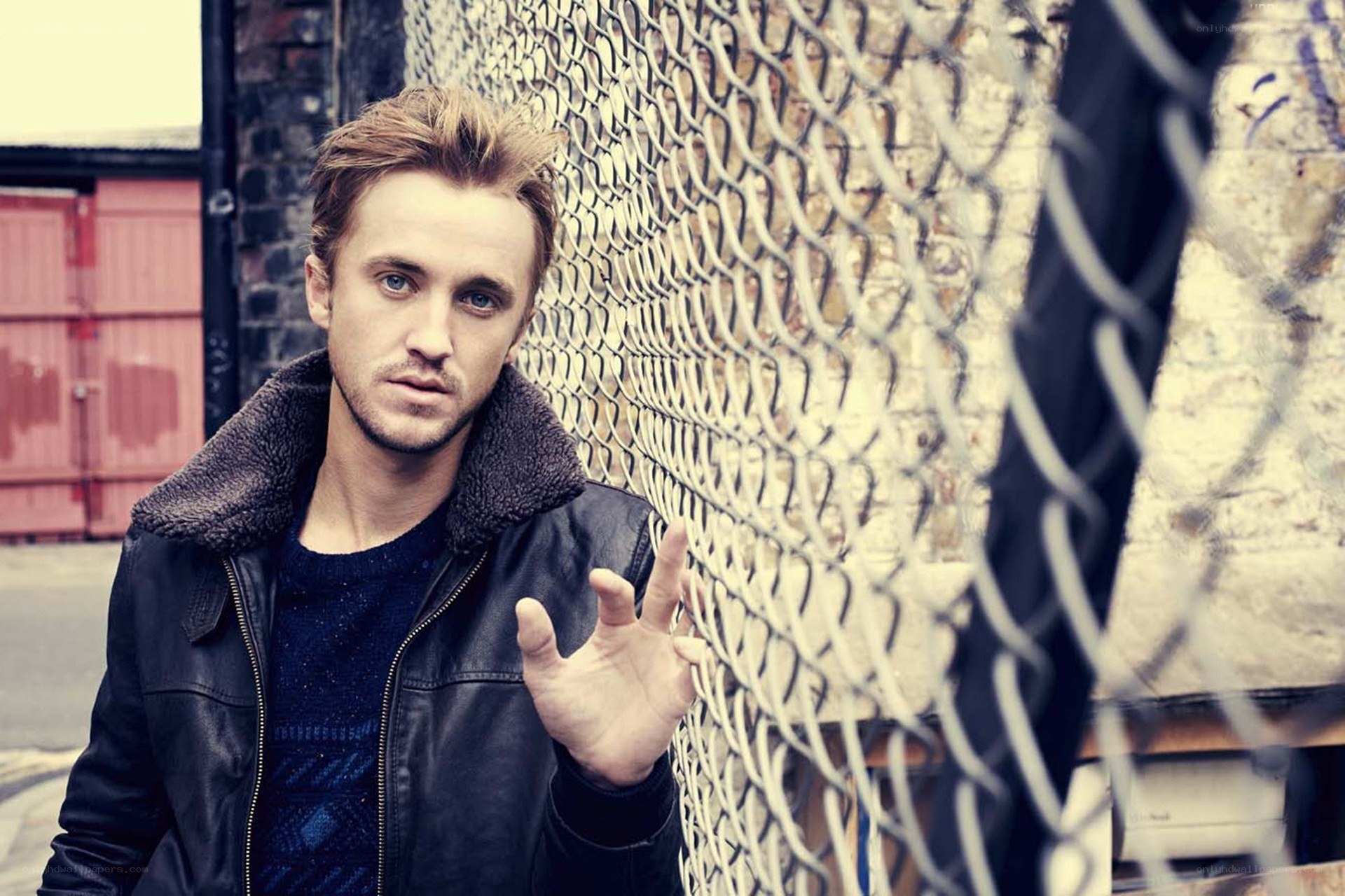 man in leather jacket by fence