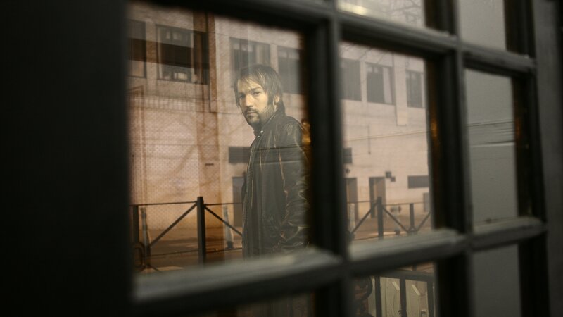 Man in leather jacket by window
