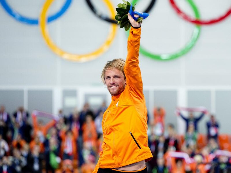 Man in Orange Jacket — Celebratory, Photograph, Olympic Rings