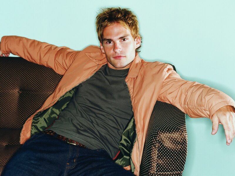 man in orange jacket on couch
