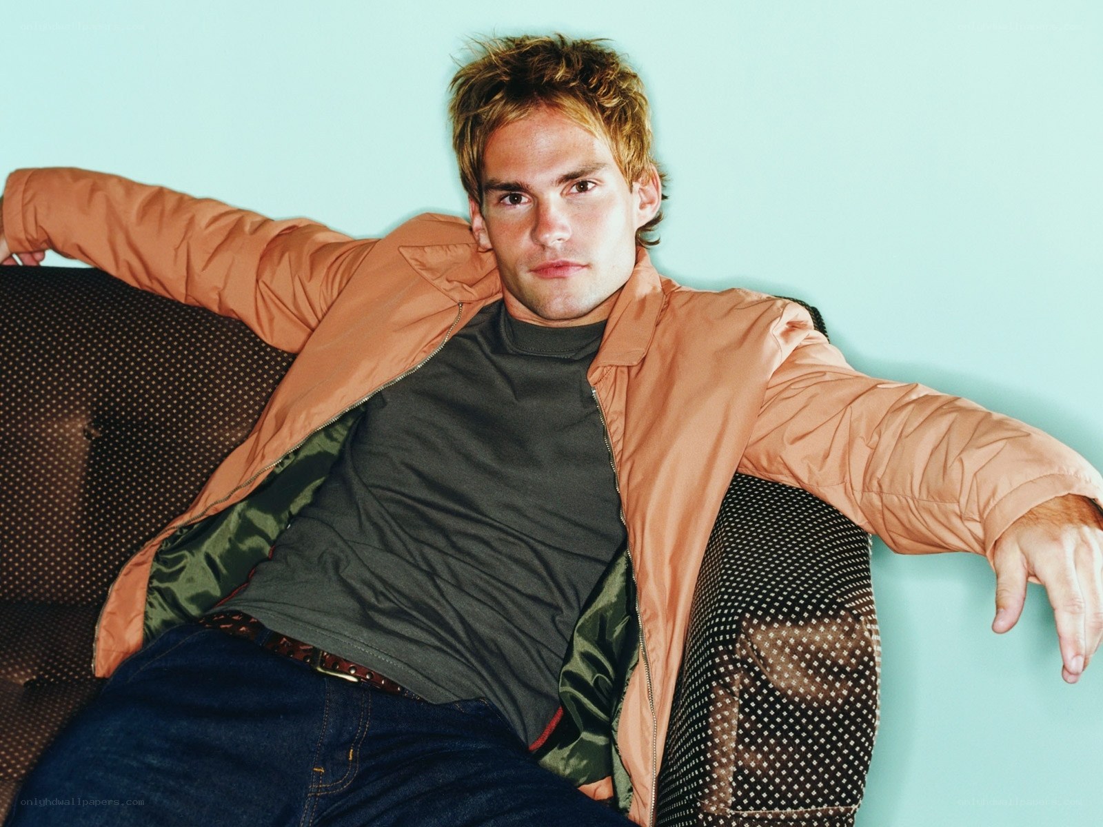 man in orange jacket on couch