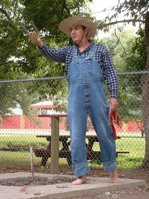 Man in overalls holding horseshoes