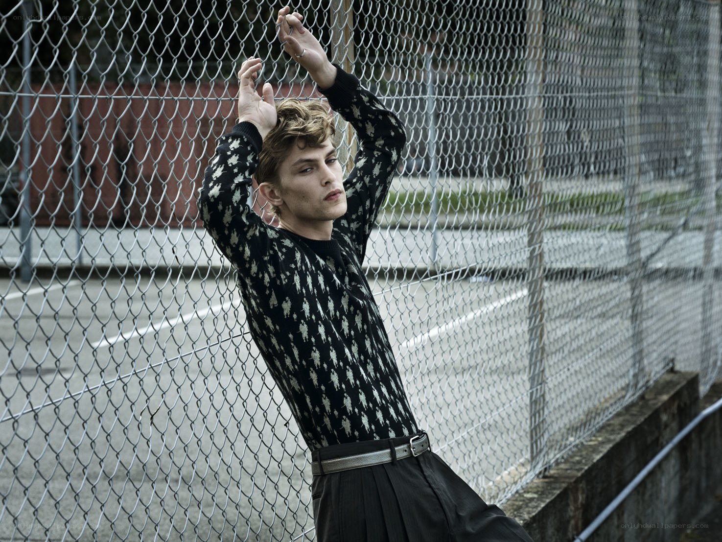 man in patterned sweater by fence