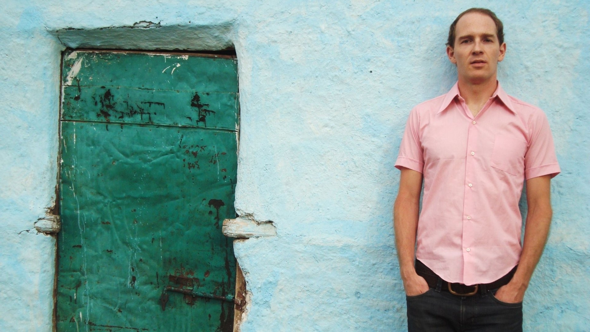 Man in pink shirt by blue wall