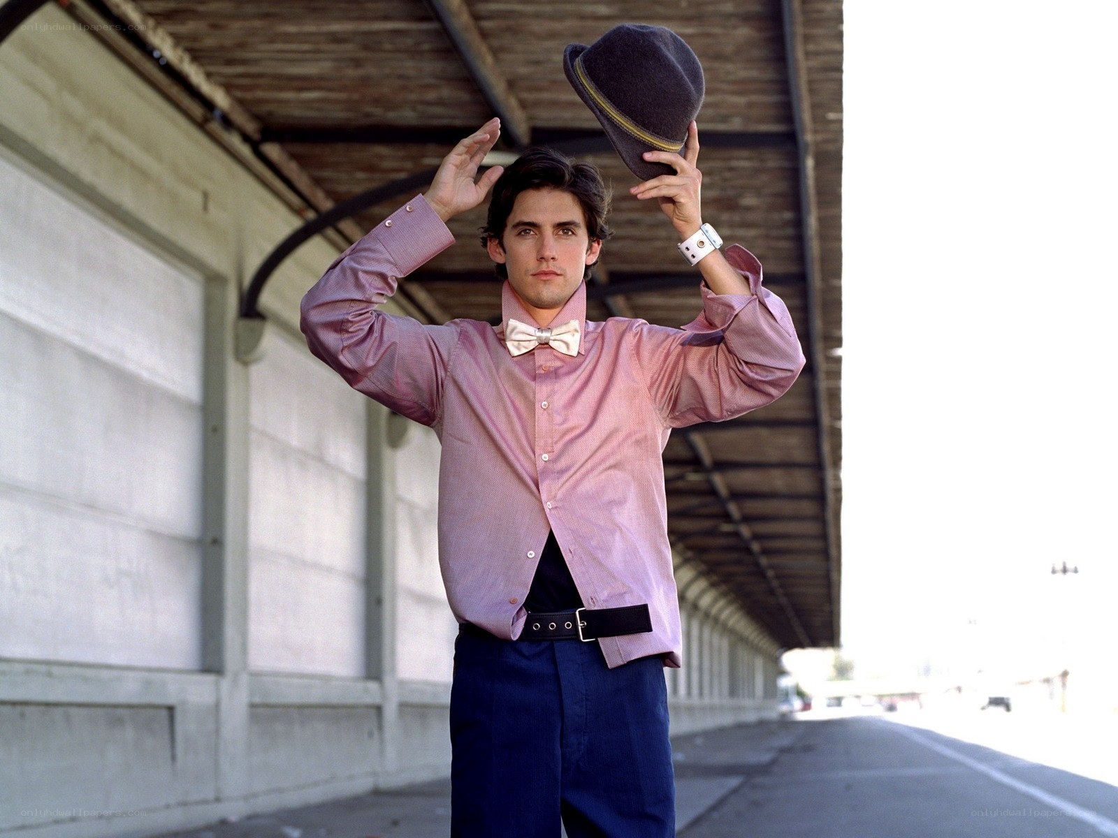 man in pink shirt holding hat