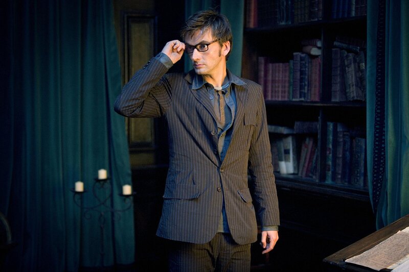 man in pinstripe suit adjusting glasses