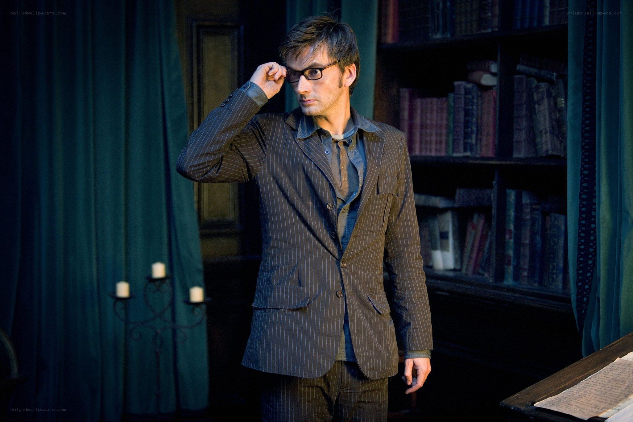 man in pinstripe suit adjusting glasses