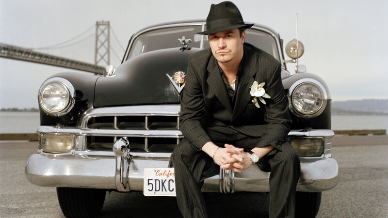 Man in pinstripe suit on car
