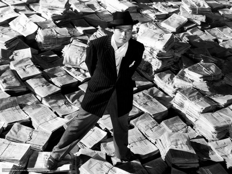 Man in pinstripe suit surrounded by newspapers