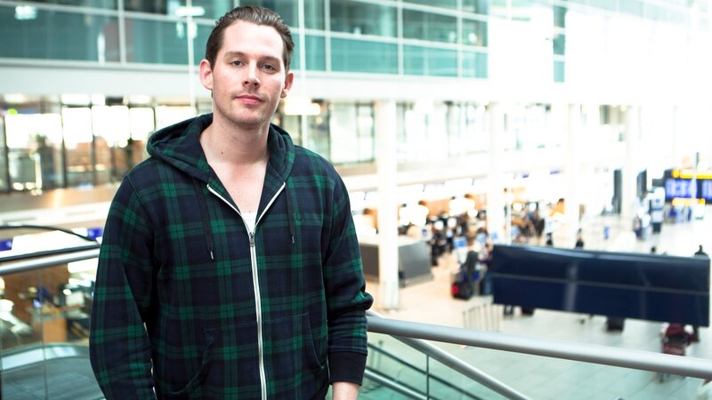 man in plaid hoodie at airport