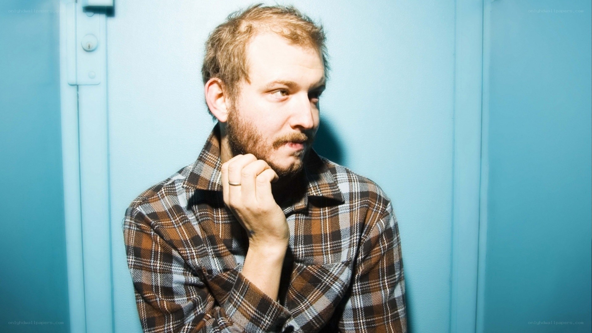 man in plaid shirt against blue wall