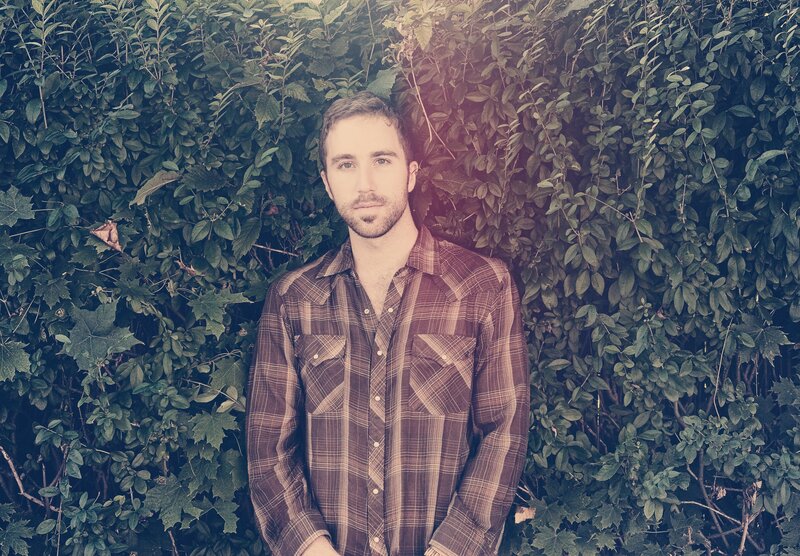 man in plaid shirt against greenery