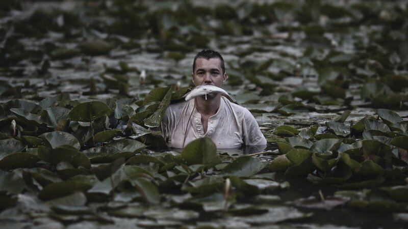 man in pond with fish