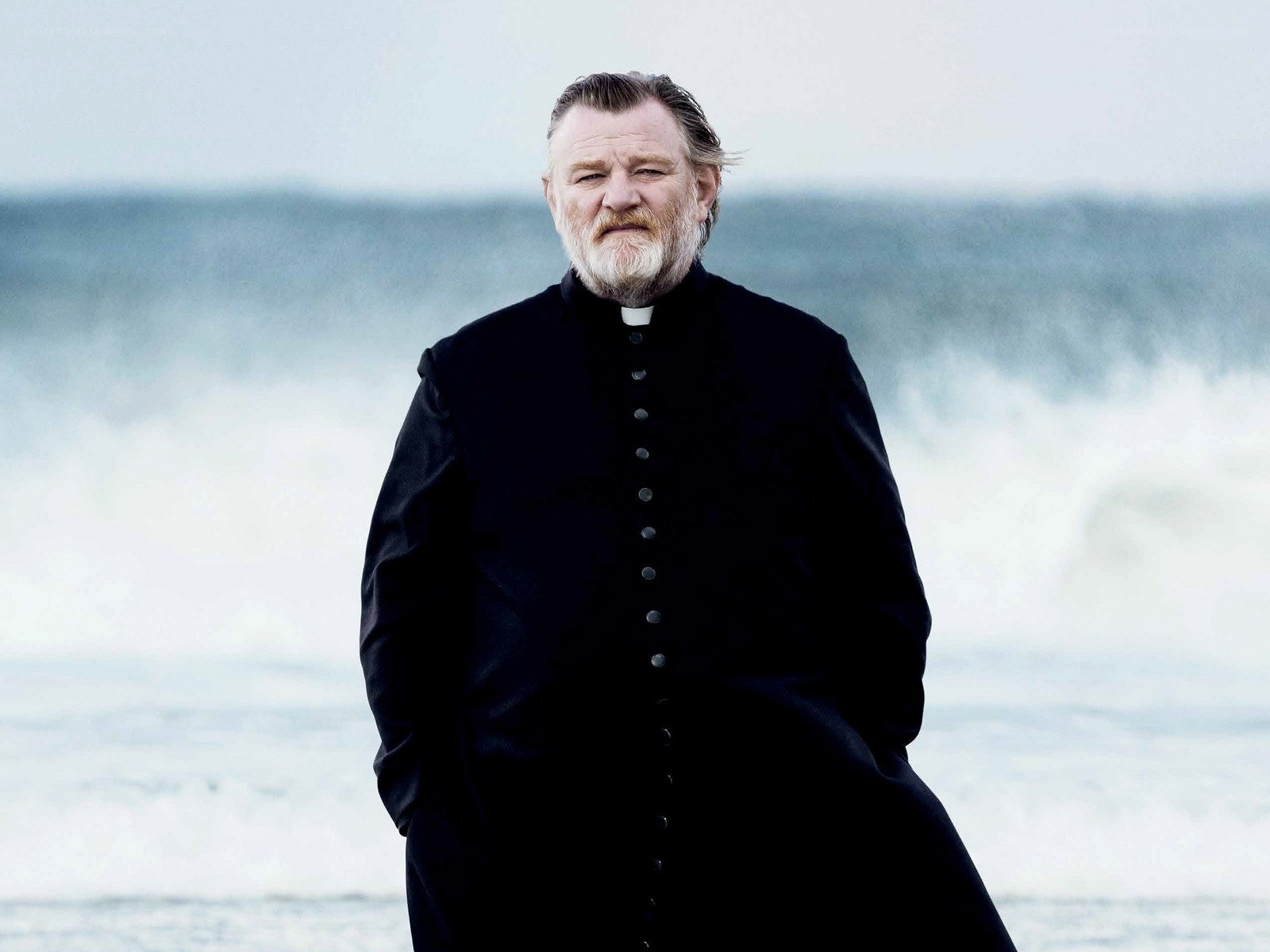 man in priest's robe on beach
