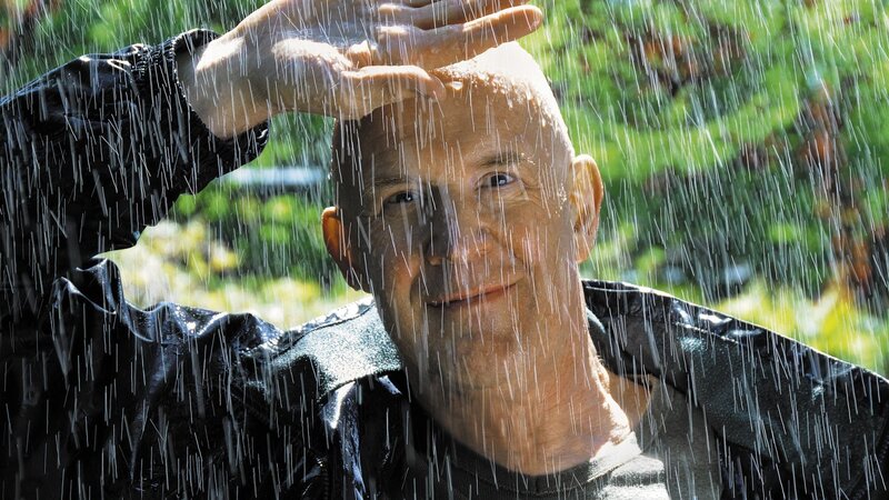 man in rain with hand on head