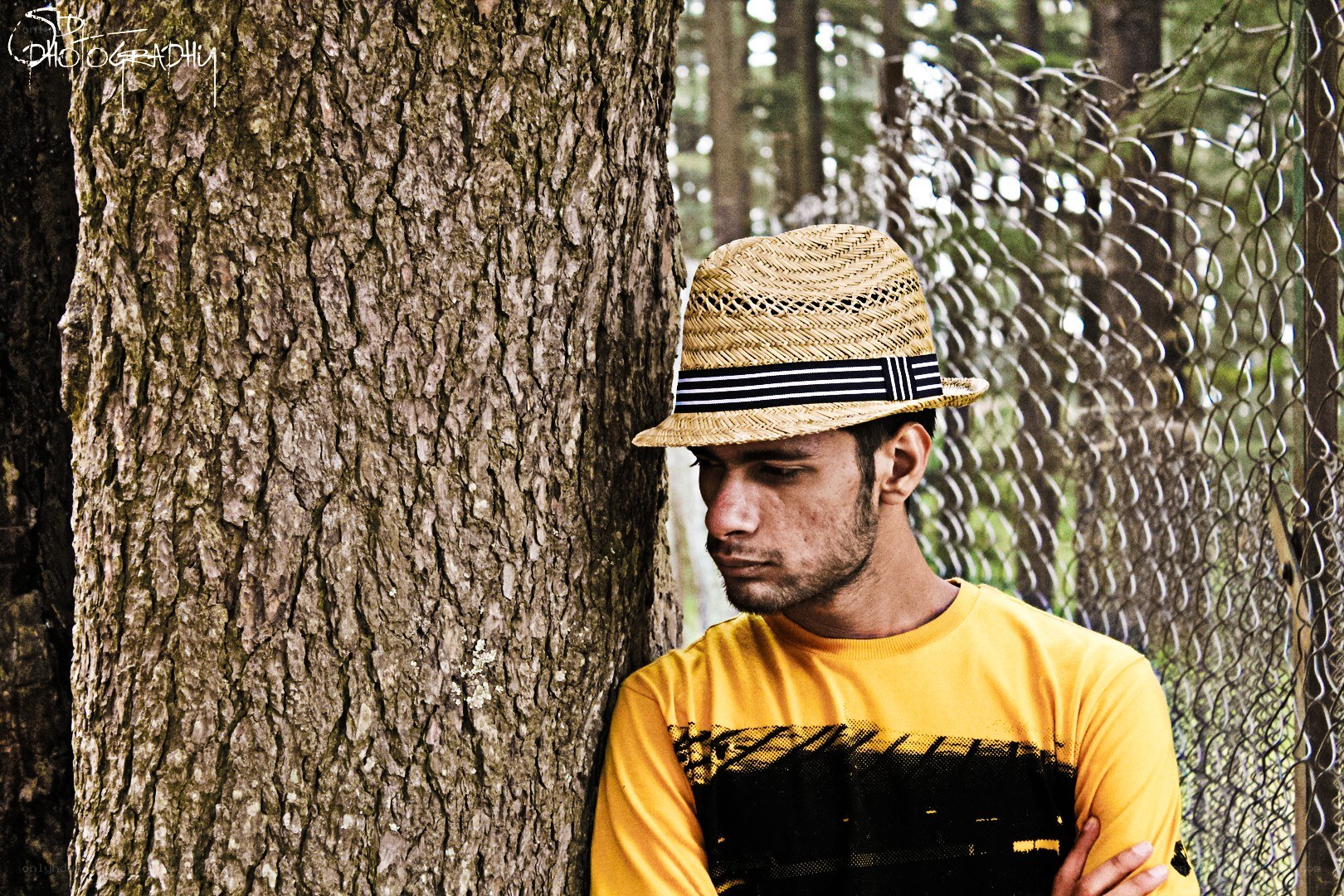man in straw hat leaning on tree