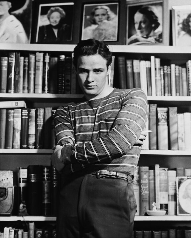 Man in striped shirt by bookshelf