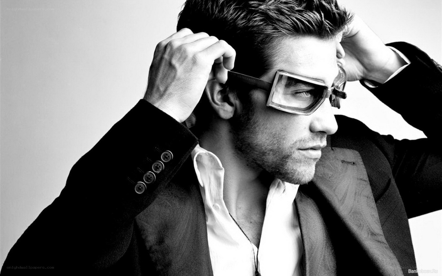 man in suit adjusting glasses