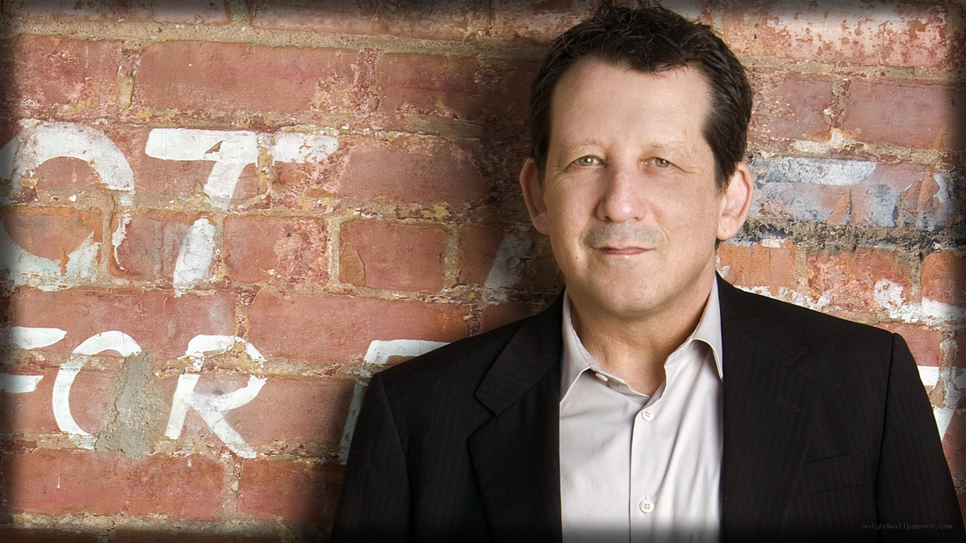 man in suit against brick wall