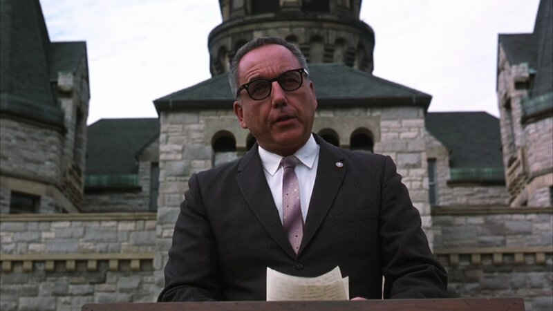 Man in Suit at Podium — Gray