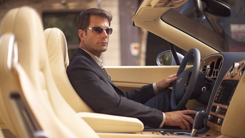 man in suit driving luxury car