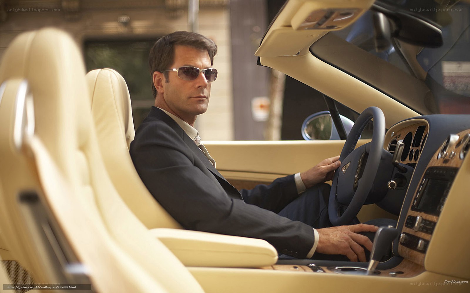man in suit driving luxury car