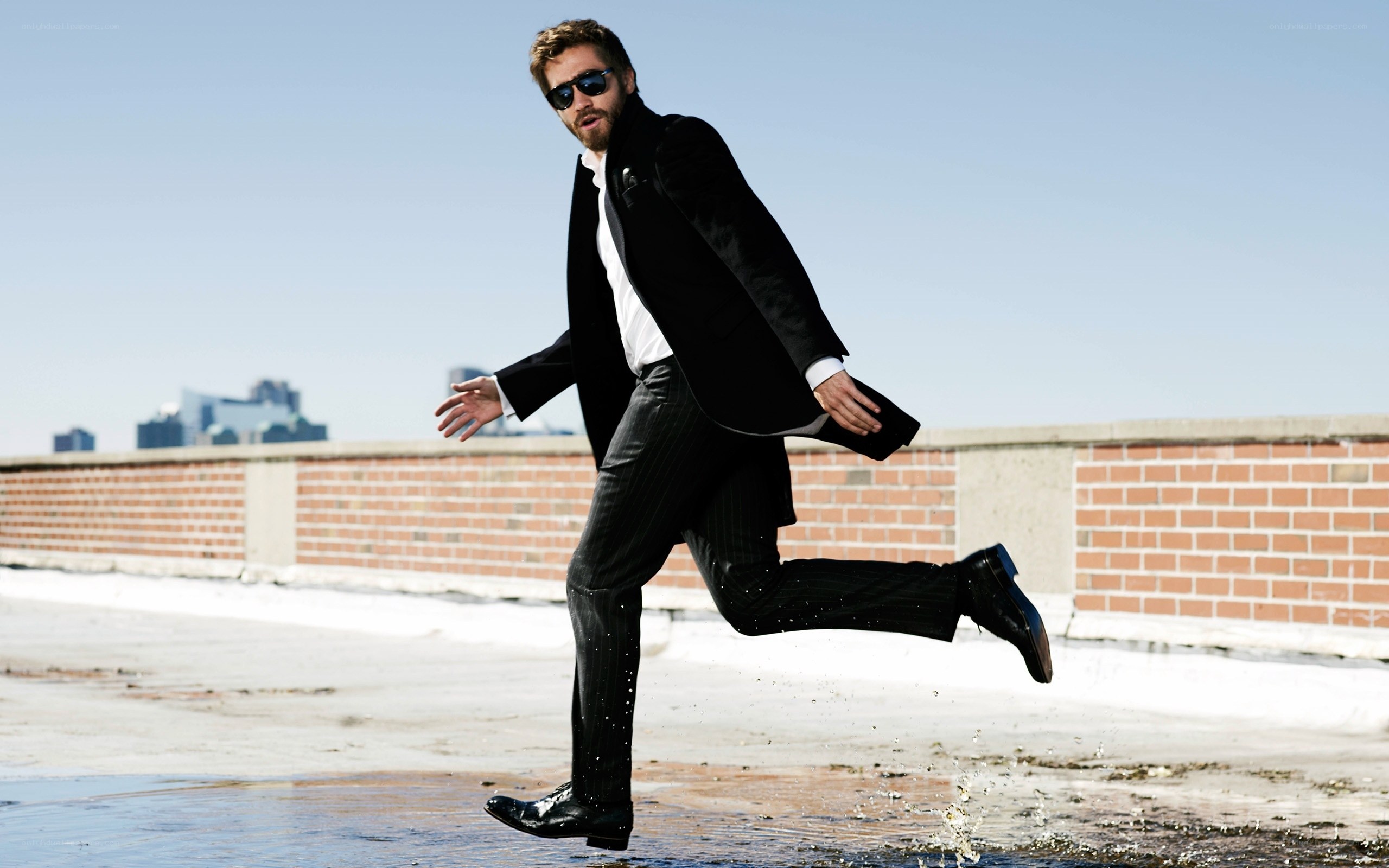 Man in suit jumping in puddle