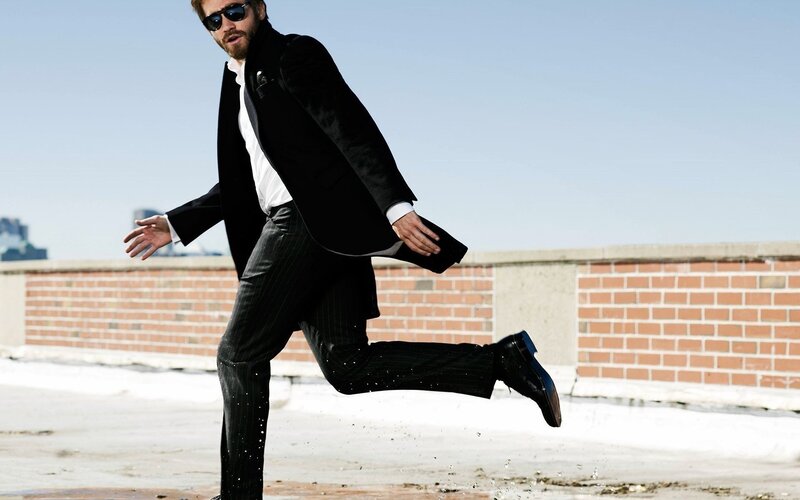 man in suit jumping on rooftop