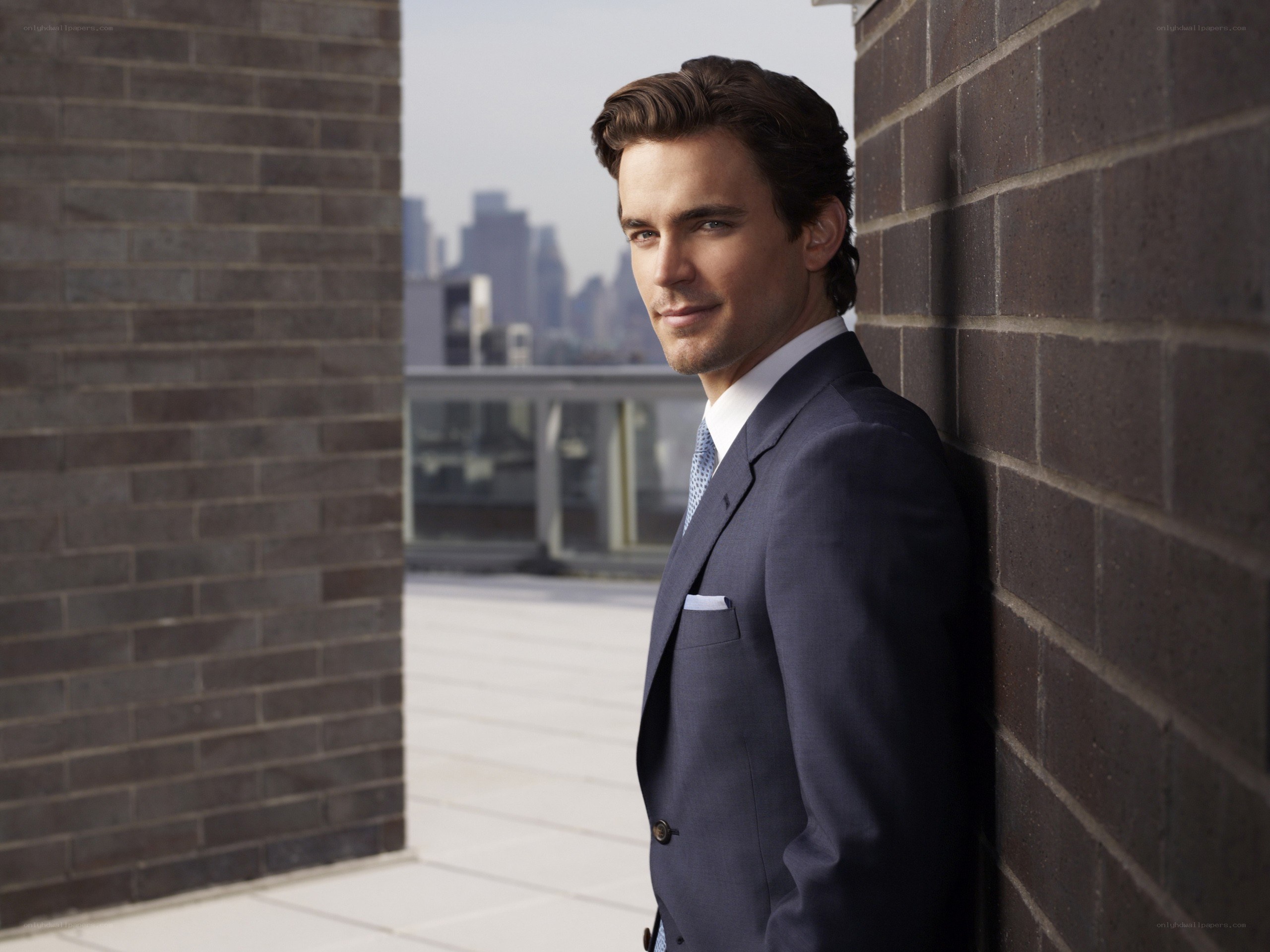 man in suit leaning on brick wall