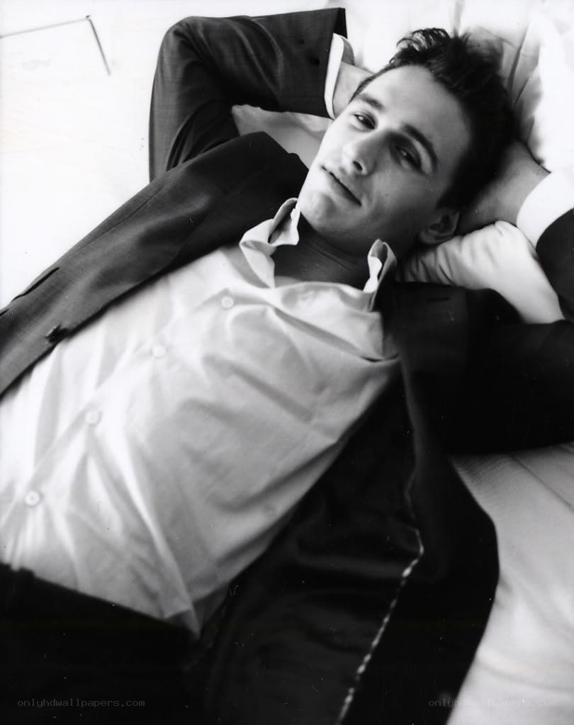 man in suit lying on bed