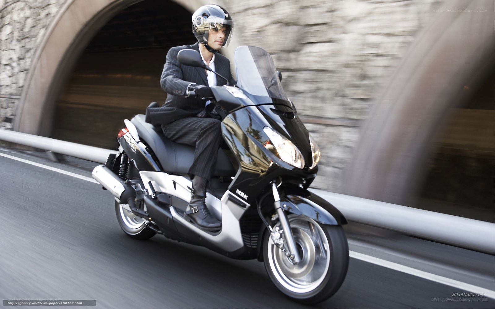 Man in suit riding scooter