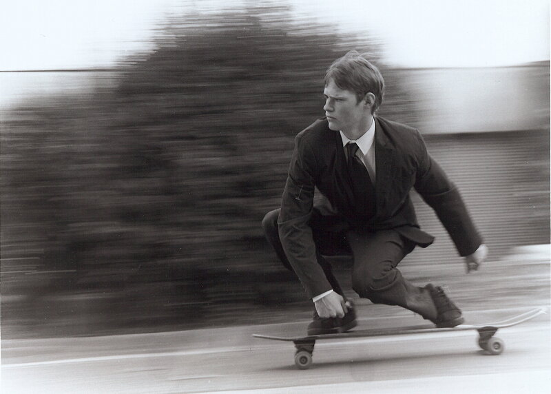 man in suit riding skateboard