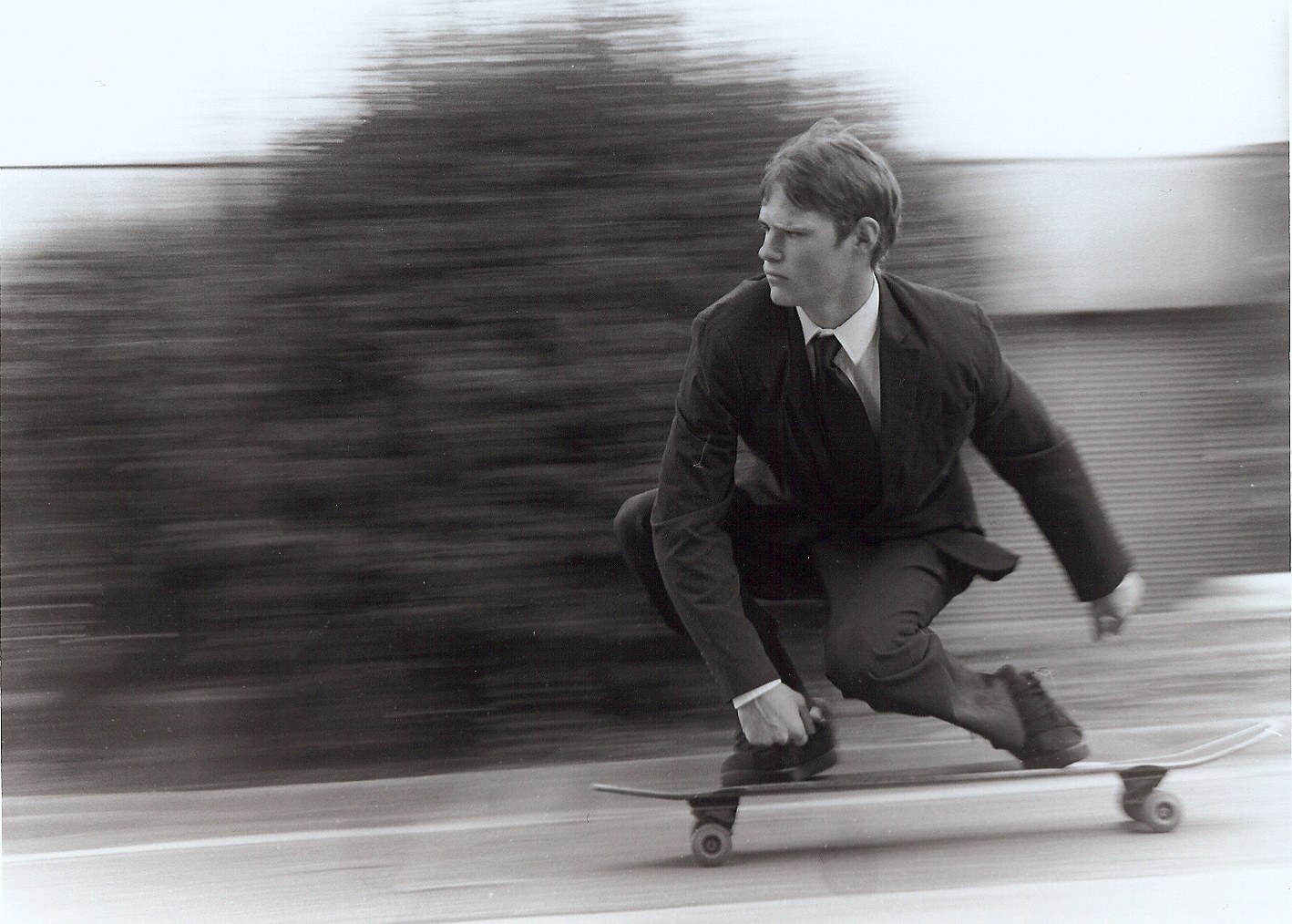 man in suit riding skateboard