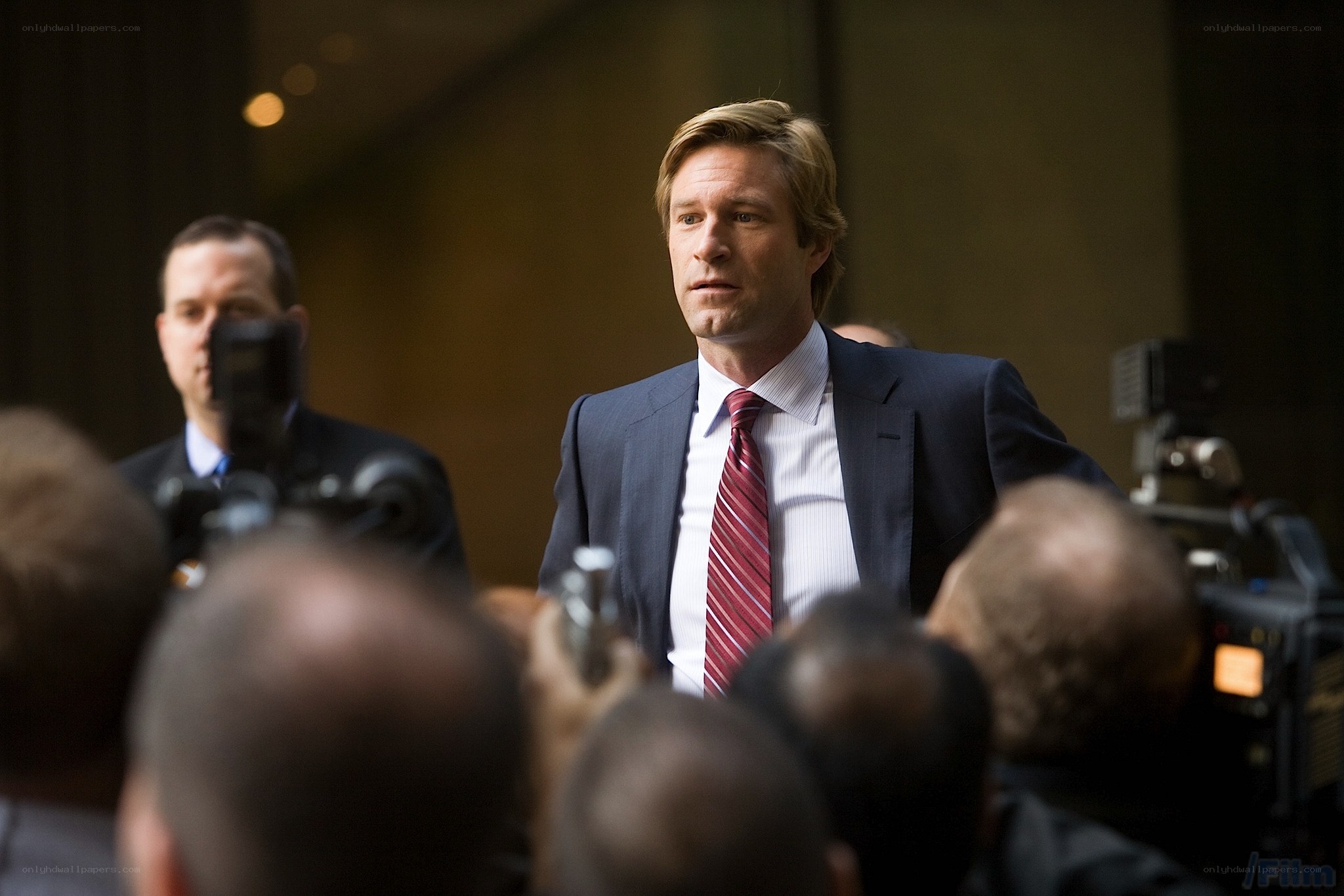 man in suit surrounded by press