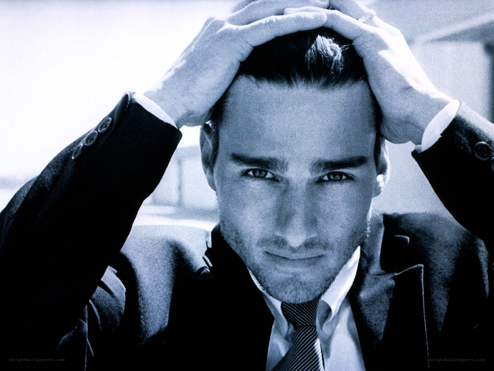 man in suit with hands on head