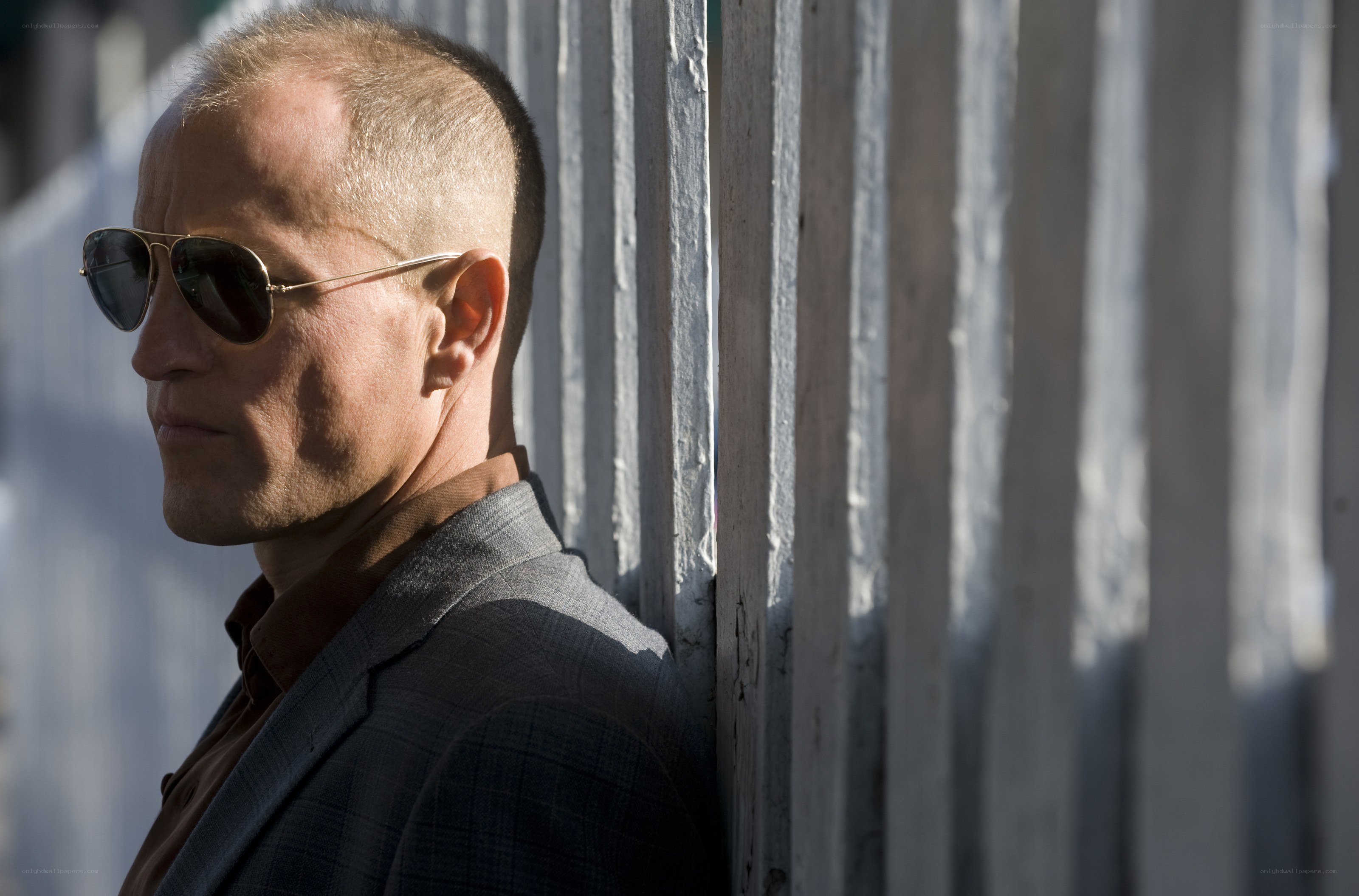 man in sunglasses leaning on fence
