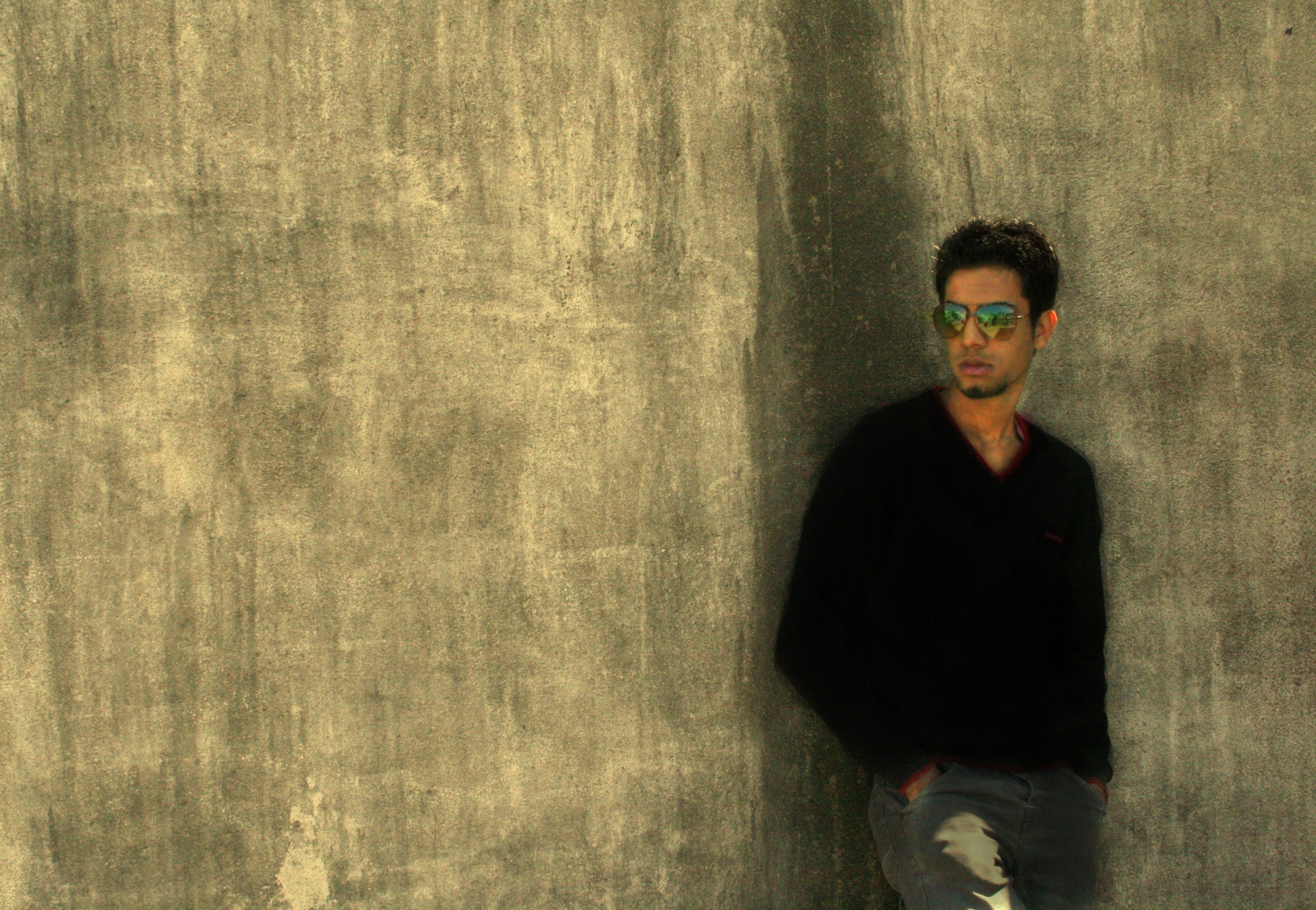 man in sunglasses leaning on wall