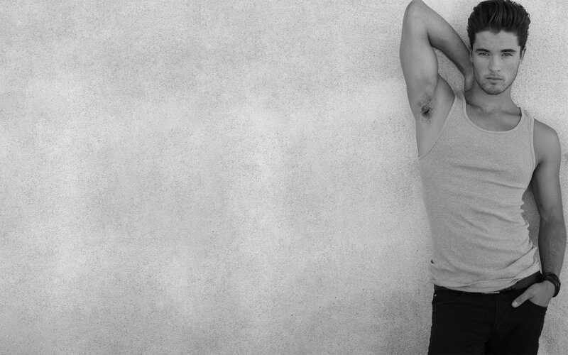 man in tank top leaning against wall