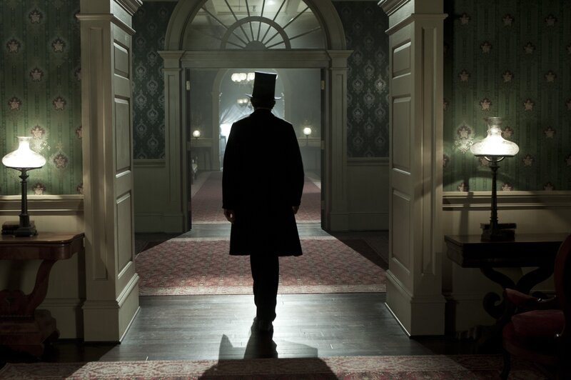 man in top hat walking through hallway