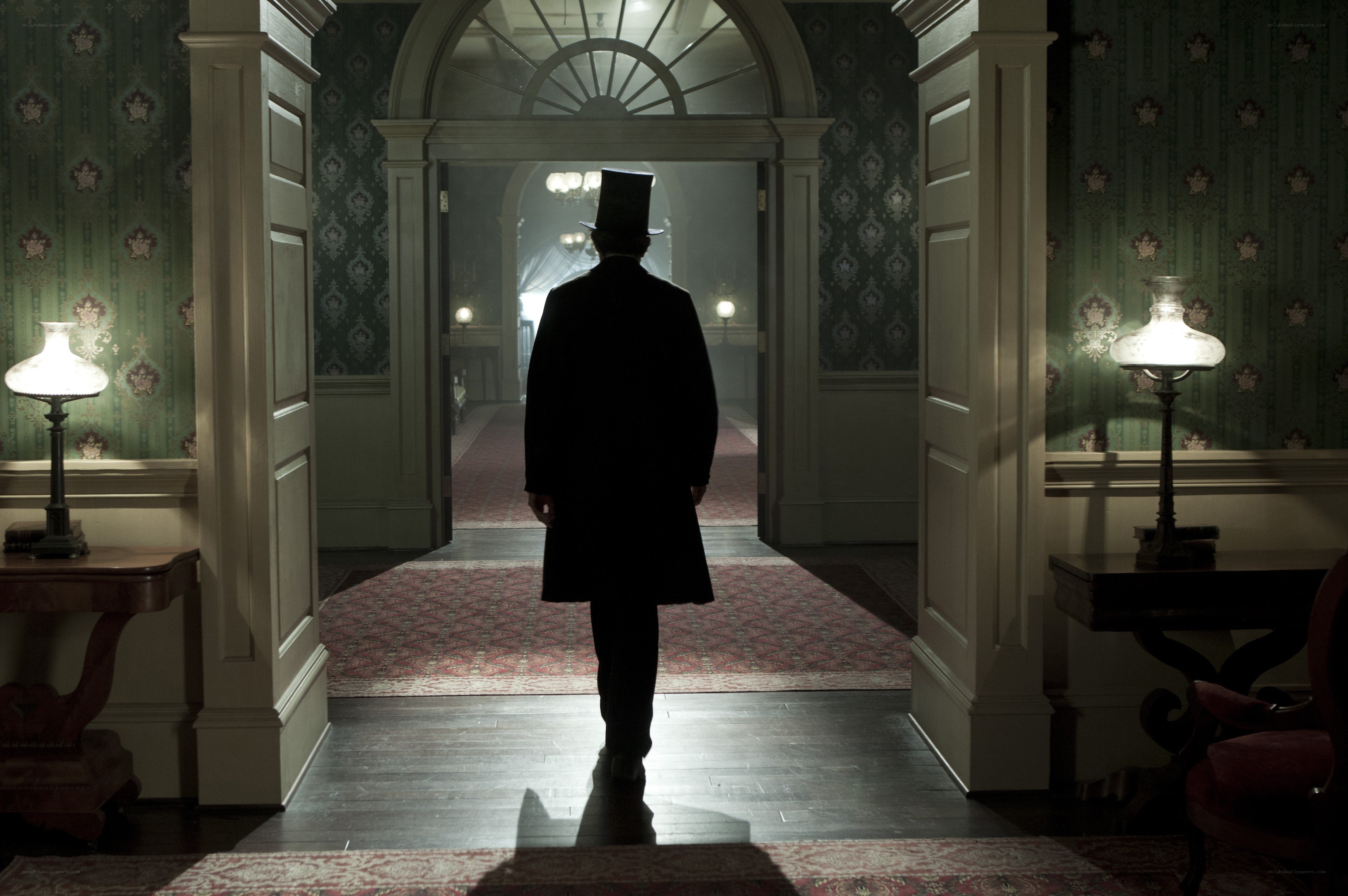 man in top hat walking through hallway