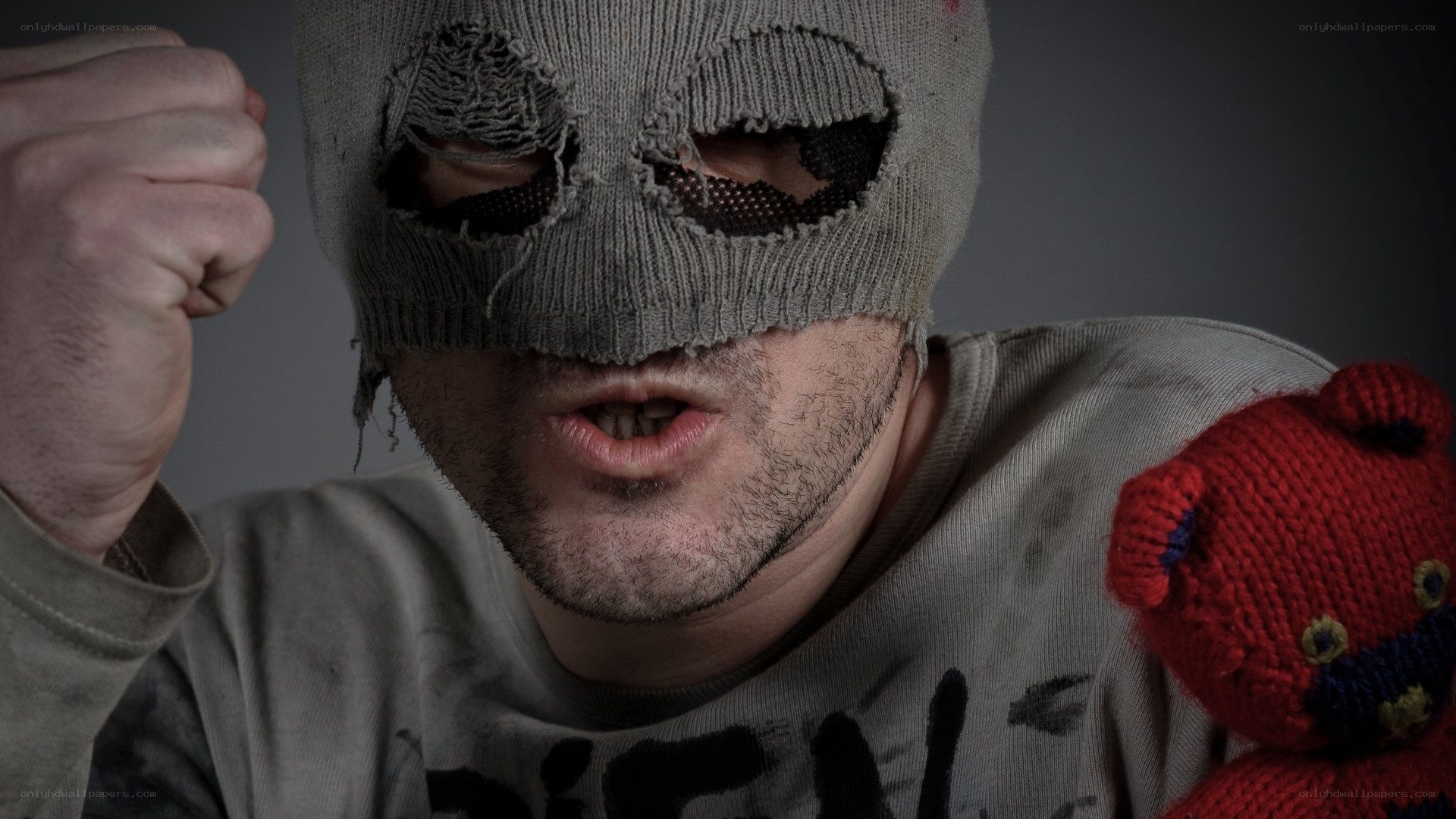 man in torn mask with teddy bear