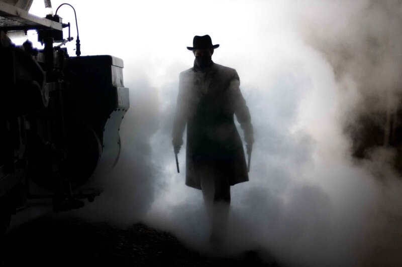 man in trench coat with guns