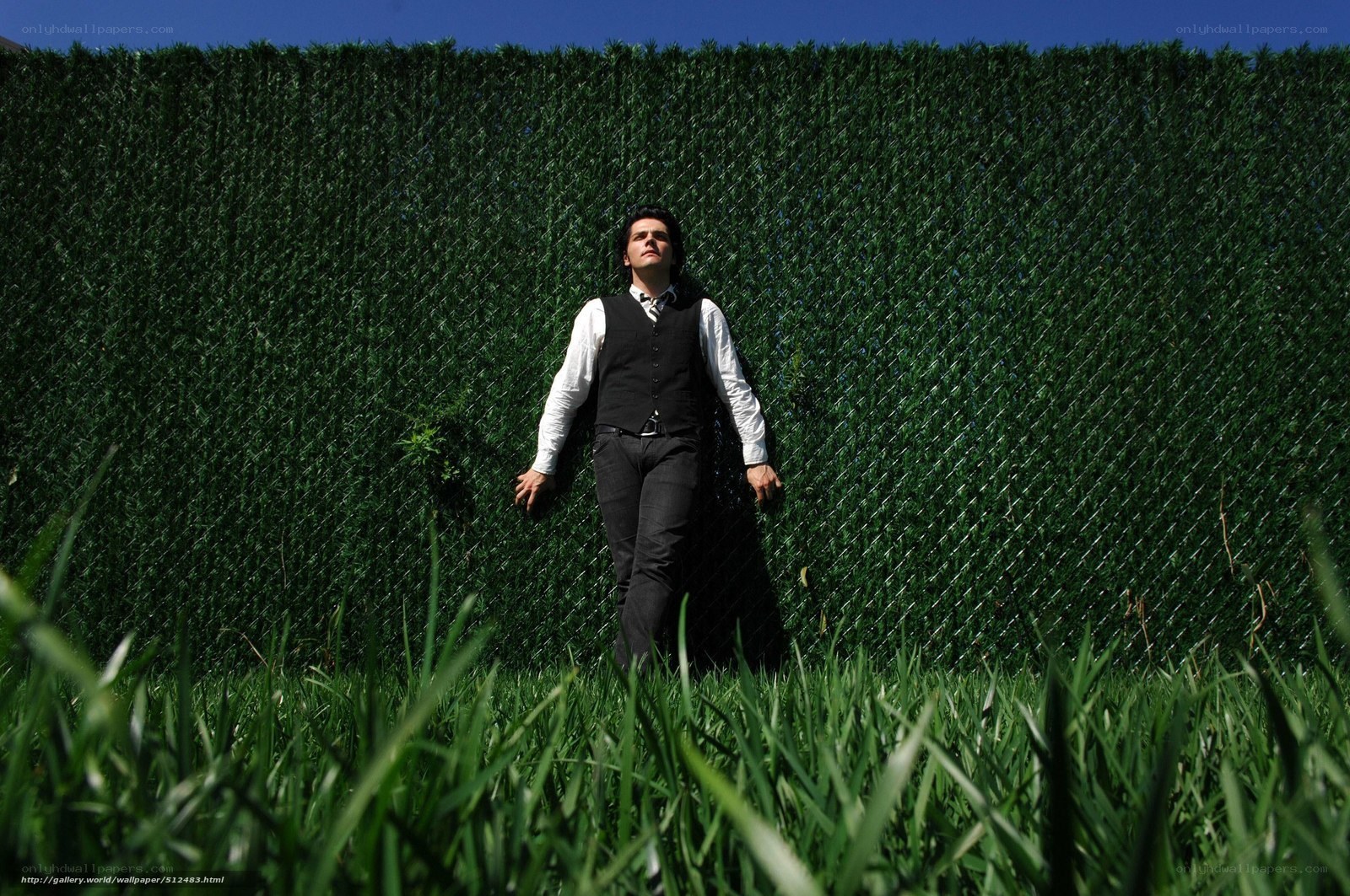 man in vest against green hedge