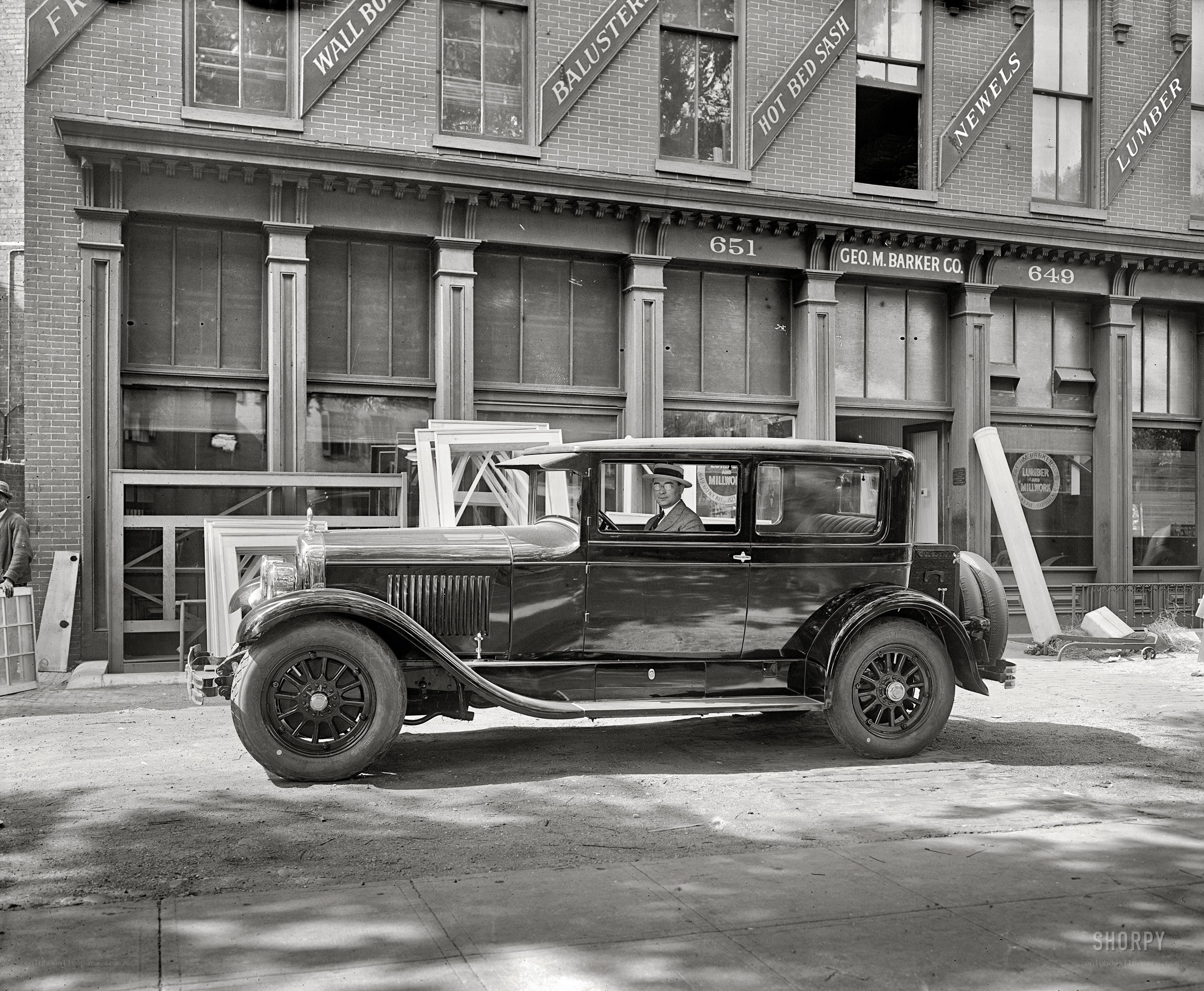 Man in vintage car outside building
