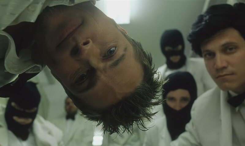 man in white coat surrounded by masked figures