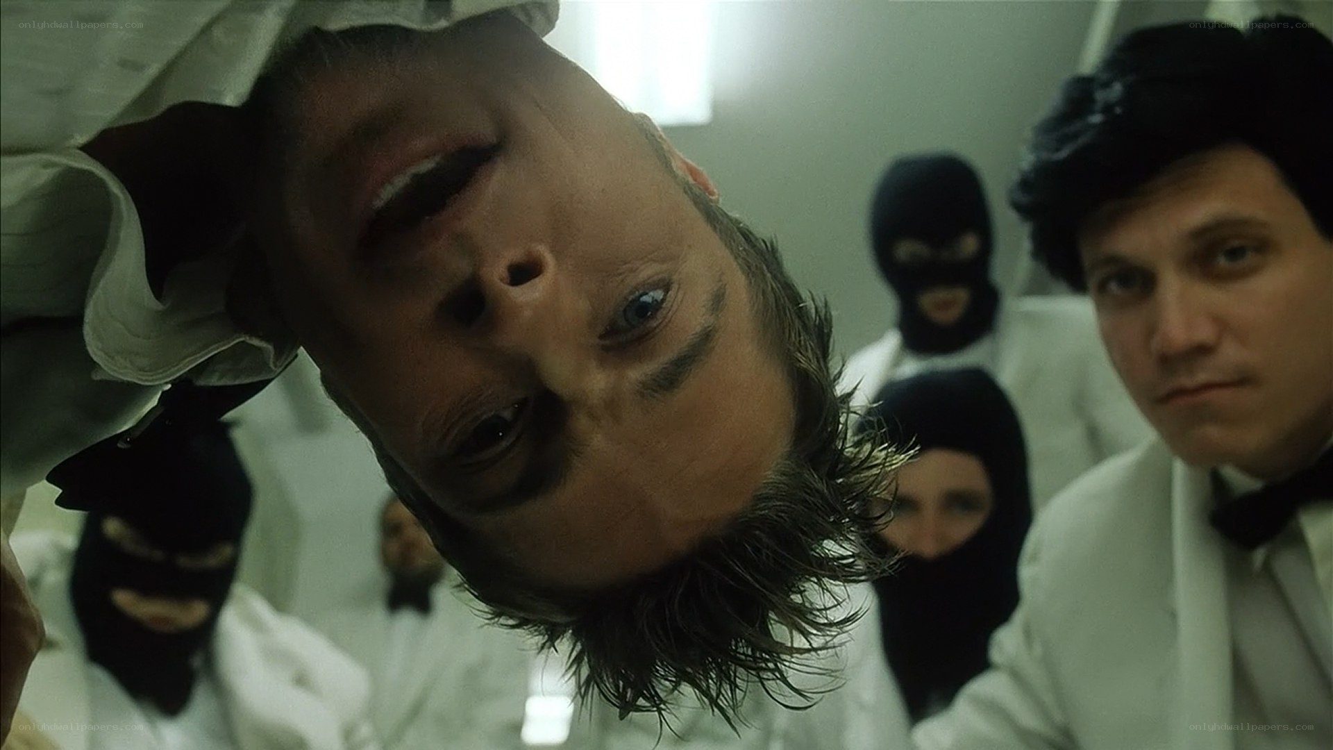 Man in white coat surrounded by masked figures