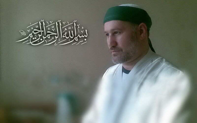 man in white robe with arabic text