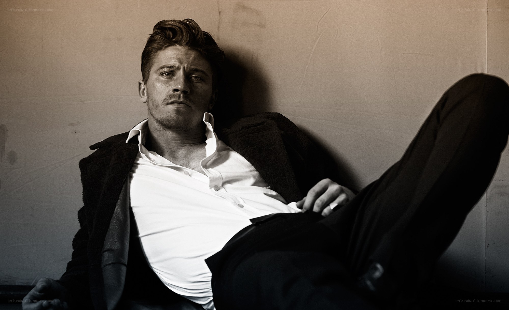 man in white shirt leaning against wall
