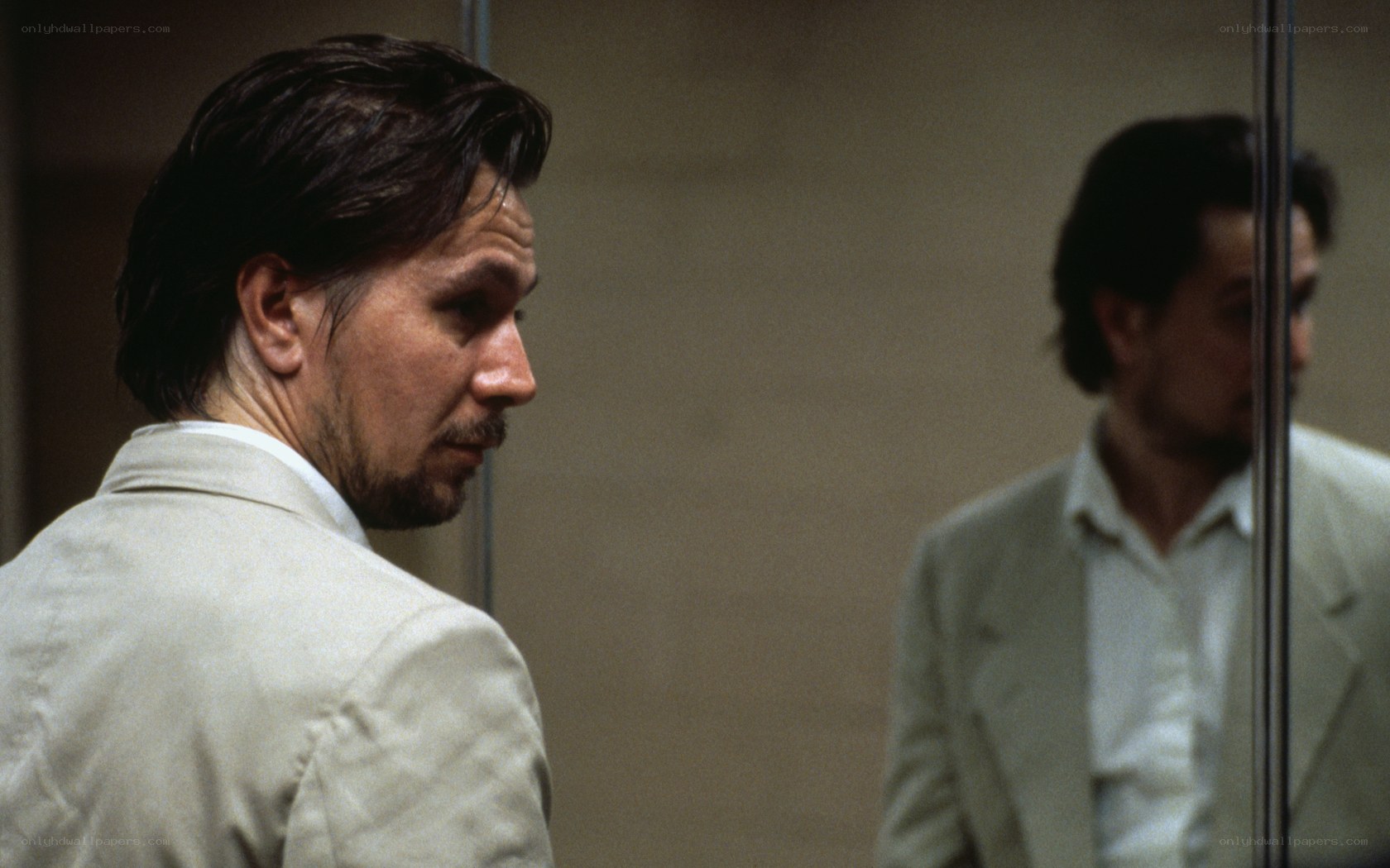 man in white suit looking at mirror
